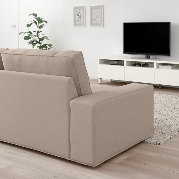 Beige KIVIK soffa i vardagsrum med tv, växt och matta.