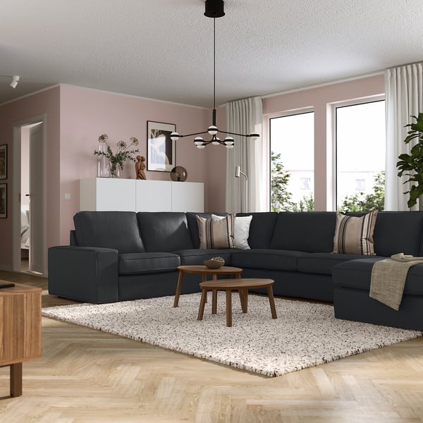 Modernt vardagsrum med soffan KIVIK, träbord, rosa väggar, naturligt ljus och taklampa.
