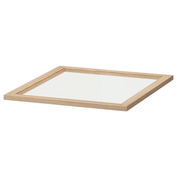 En ikea KOMPLEMENT glashylla i klar. Den är fyrkantig med en ljusbeige träram och tillverkad av träfiberskiva och härdat glas.
