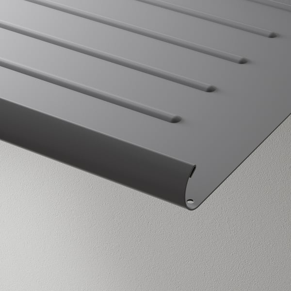 En närbild av en modern, grå metallhylla med en lutande design, med flera åsar för luftcirkulation.