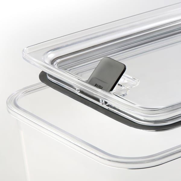 Genomskinlig plastburk med låsbart lock och ventilationsknapp, staplad prydligt på en vit yta.