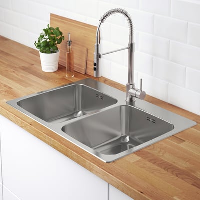 Dubbel diskbänk i rostfritt stål med elegant kran och modern bänkskiva.