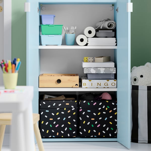Ett ljusblått förråd med öppna och stängda sektioner. Den rymmer lådor för kontorsmaterial, spel och tyg, perfekta för att organisera olika saker prydligt.