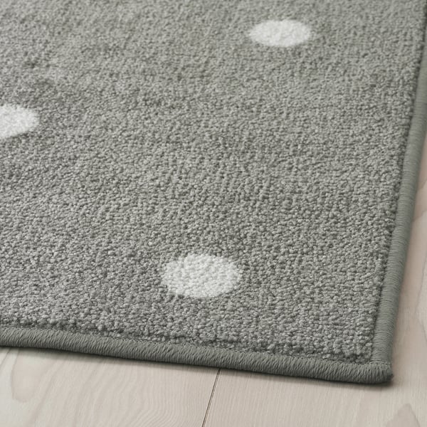 Grå rektangulär matta med vita prickar, lagd på ett trägolv, med en slitstark, strukturerad yta och säker gummibaksida.