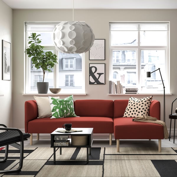 Modernt vardagsrum med röd soffa LILLEHEM, stora fönster, växt och svart soffbord.