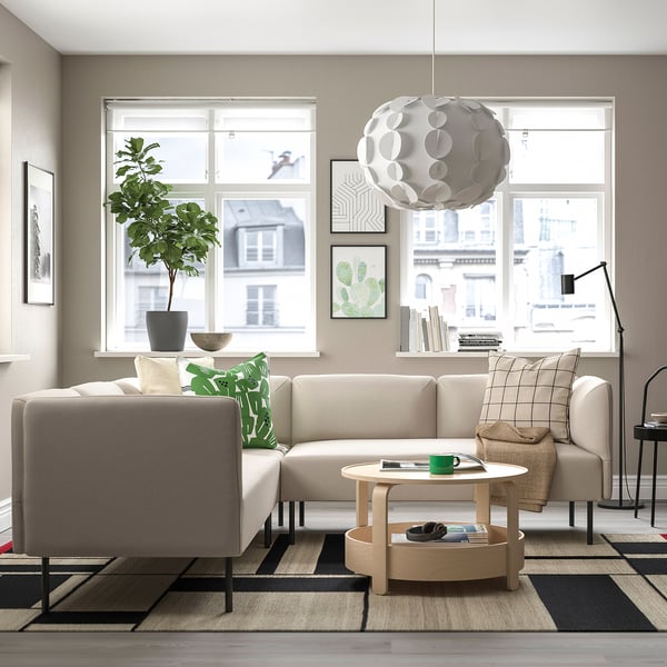 Modernt vardagsrum med beige LILLEHEM soffa, gröna kuddar, soffbord i trä, matta, golvlampa och krukväxt vid fönstret.