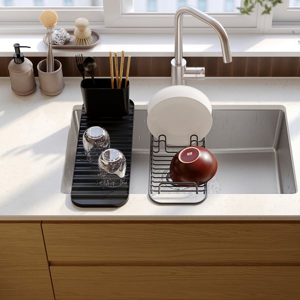 Diskho med LILLHAVET diskställ, torktallrikar, glas och äpple; bestick, tvålautomat och växt i närheten.