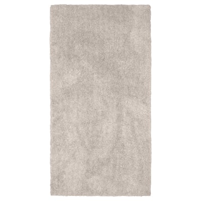 En rektangulär, beige matta LINDKNUD. Den är tillverkad av återvunnen polyester och har en mjuk, plyschyta som är idealisk för sovrum.