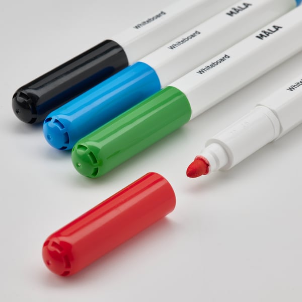 Fyra MÅLA whiteboard-pennor på vit yta. Kapsyler i svart, blått, grönt, rött. En utan lock visar röd bläck. Barnvänliga grepp. Kreativt set.