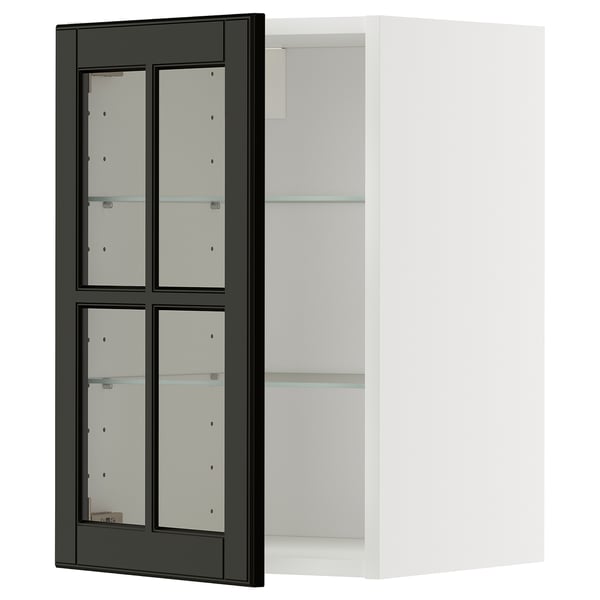 Ett ikea METOD köksskåp med svarta bodbynglasdörrar och vit ram. Skåpet har justerbara glashyllor och en modern design.