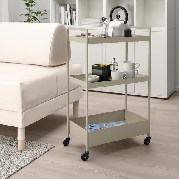 NISSAFORS beige rullvagn, liten, 3-vånings, metall, nära vit soffa, innehållande köksartiklar.