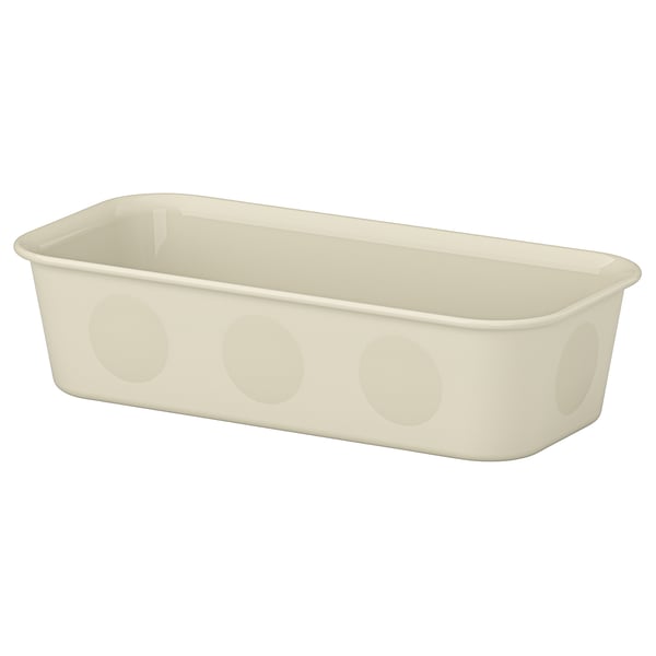 En beige NOJIGG organisatörslåda. Den är rektangulär, tillverkad av återvunnen plast och cirkulära utskärningar på sidorna.