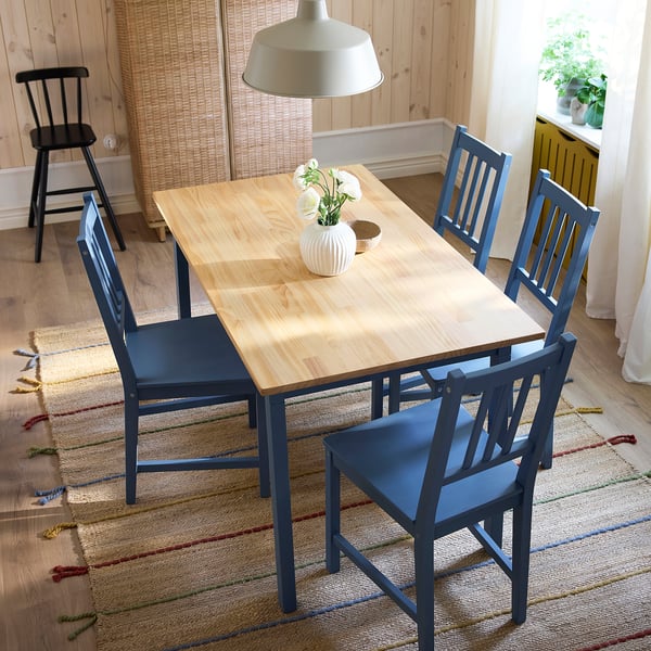 Modern matplats med ljust träbord och blå stolar, lämplig för små utrymmen.