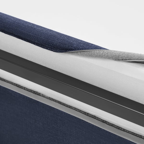 Närbild på RAMNEFJÄLL klädd sängstomme. Visar mjuk, vadderad sänggavel med böjd design och avtagbart, maskintvättbart överdrag med passpoalkanter.