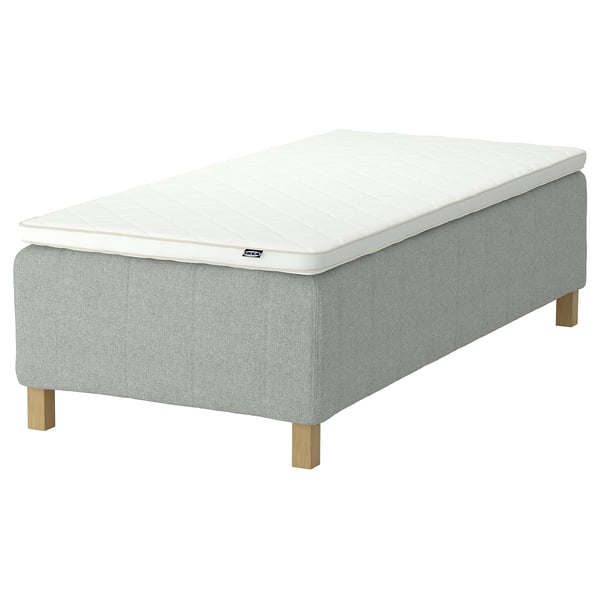Rektangulär stoppad sängbotten, grått tyg, ljusa träben, fast madrassunderlägg och modern minimalistisk design.
