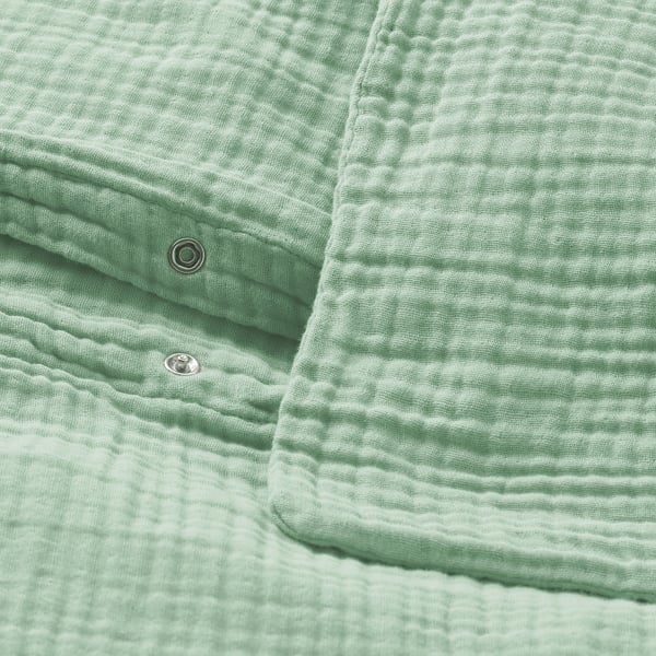 Ljusgrönt påslakanset med vågig struktur och metallförslutningar, tillverkat av gots-certifierad ekologisk bomull.