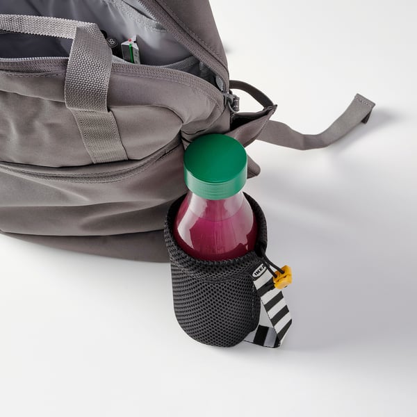 En återanvändbar flaska med grönt lock ligger i en grå påses sidoficka, perfekt för att bära kalla drycker när du är på språng.