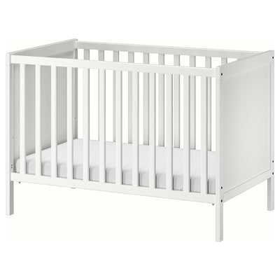 En vit SUNDVIK spjälsäng i trä med justerbar madrasshöjd och avtagbar sidopanel, designad för barnets säkerhet och komfort.