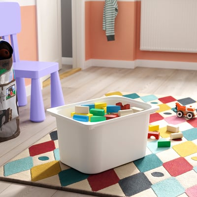 Leksakslåda i plast med färgglada block på en lapptäcksmatta. Perfekt för förvaring av barnleksaker.