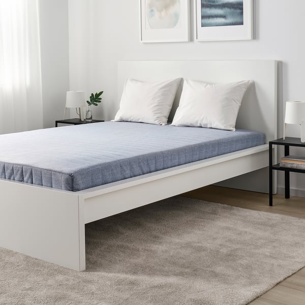 Modernt sovrum med vit säng, grå matta, svarta nattduksbord och minimalistisk inredning.