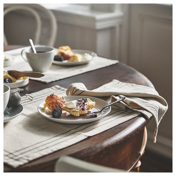 Mysig frukost med scones, kaffe och bakverk på beige matta.