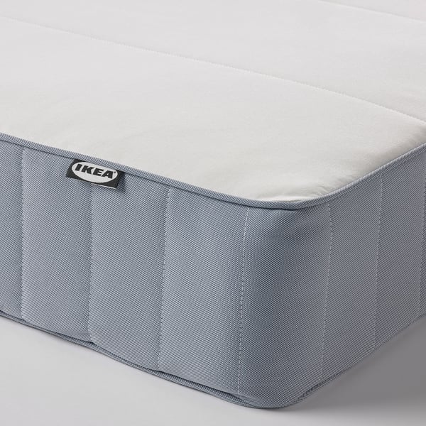 Vanlig grå bäddmadrasshörna med ikea-etikett, fast med synlig quiltad struktur, lovar bra stöd och andningsförmåga.