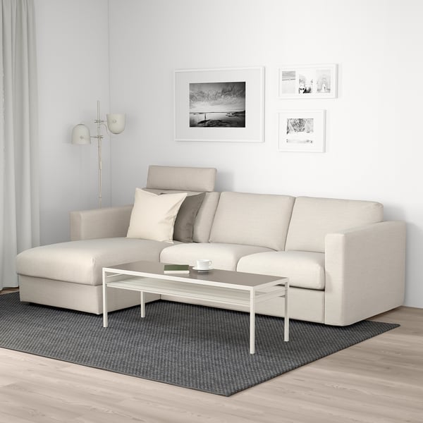 Modernt vardagsrum med VIMLE beige soffa, vitt soffbord, grå matta och väggkonst.
