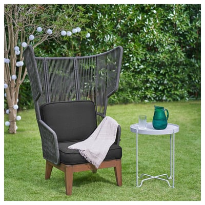 Mörk wingback stol, gröna glasvaror, gräsbevuxen bakgrund.