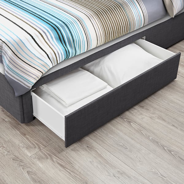 Under-bed storage drawers, part of BALESTRAND bedframe, holding folded white sheets on wooden floor.