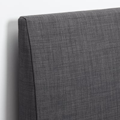 Close-up of high-quality, upholstered headboard with smooth fabric against white wall.