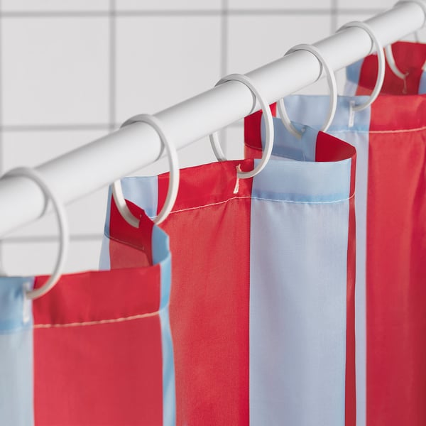 Red and blue striped shower curtain hangs on white rod with rings, water-repellent.