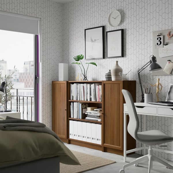 Cosy room with BILLY bookshelf, plants, chair, and geometric wallpaper.