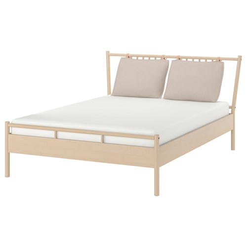 BJÖRKSNÄS light wooden bed with beige pillows and white mattress.