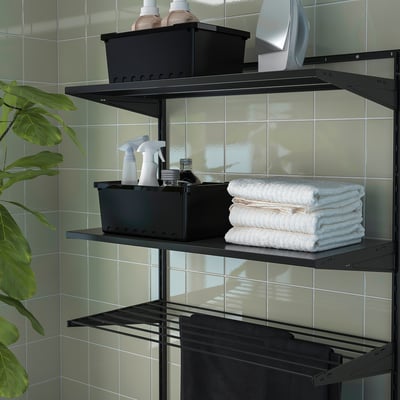 Shelf storage unit holds towels, bottles, and a dryer. Mounted on tiled wall, efficient for laundry rooms.