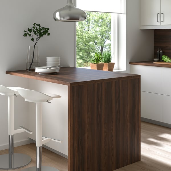 Modern kitchen with EKBACKEN island, wooden counter, white stools. Large window reveals outdoor greenery.