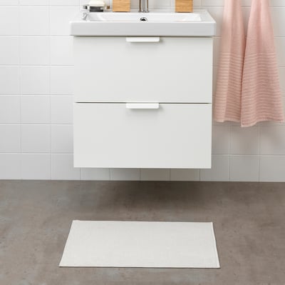 Modern bathroom with white FINTSEN mat, sink, and towel. Mat is rectangular, fits under sink, made of recycled polyester.