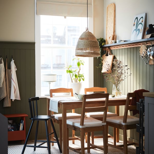 Cosy kitchen table by window with cushioned chairs and bamboo tray.
