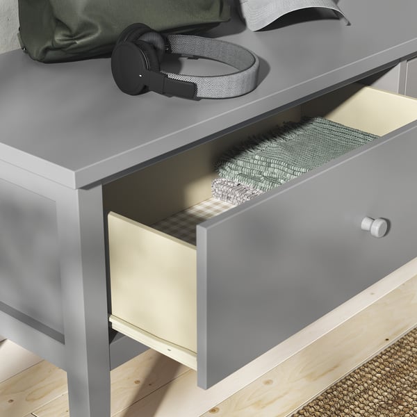 Grey GULLABERGg drawer, partially open with clothes, square knobs, tapered legs.