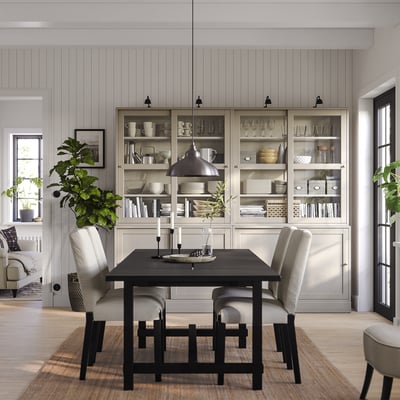 Minimalist dining area with HAVSTA sidesboard, table, chairs, lamp, plants, and glass cases.
