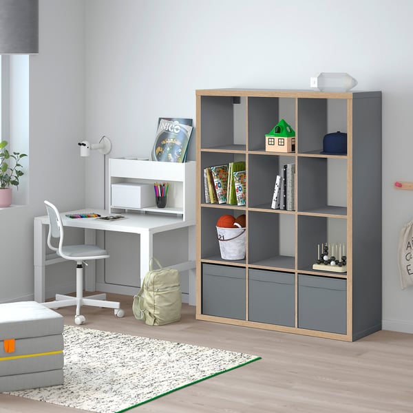 Grey KALLAX shelving unit in living space, holding toys, books, and decor.