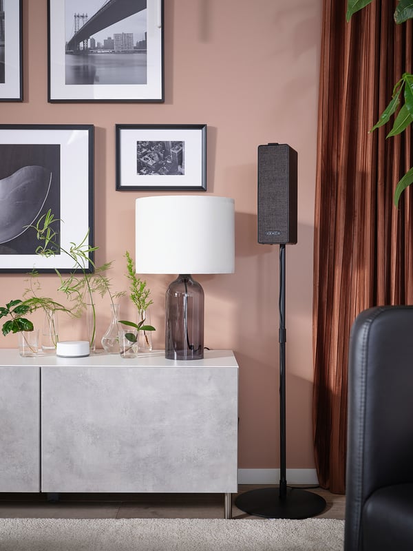 Modern living space with sleek KALLVIKEN cabinet, pink walls, tall speaker, lamp, and plants.