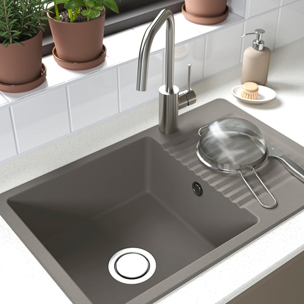 Black sink with stainless tap and strainer; plants nearby.