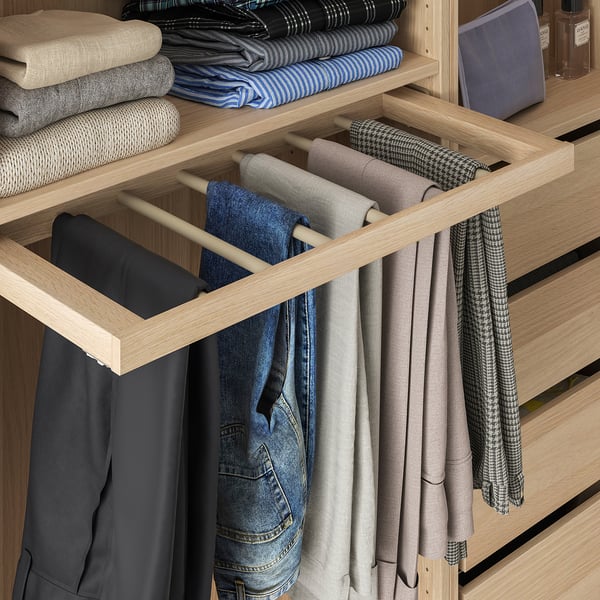 A wooden trousers hanger pulled out for easy access, holding multiple pairs of neatly organised pants in a pax wardrobe.