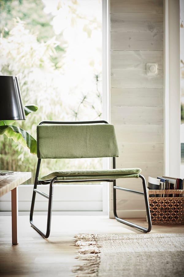 Minimalist green chair, metal frame, soft seat, modern design, by window.