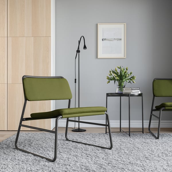 Modern minimalist corner with LINNEBÄCK green chairs, sleek black metal frames, textured grey rug, and simple decor.