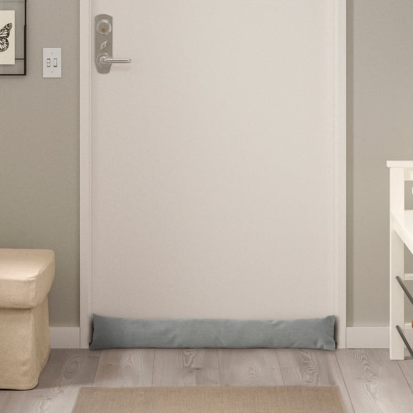 Small grey door draught stopper on floor under door, minimal design complements any space.