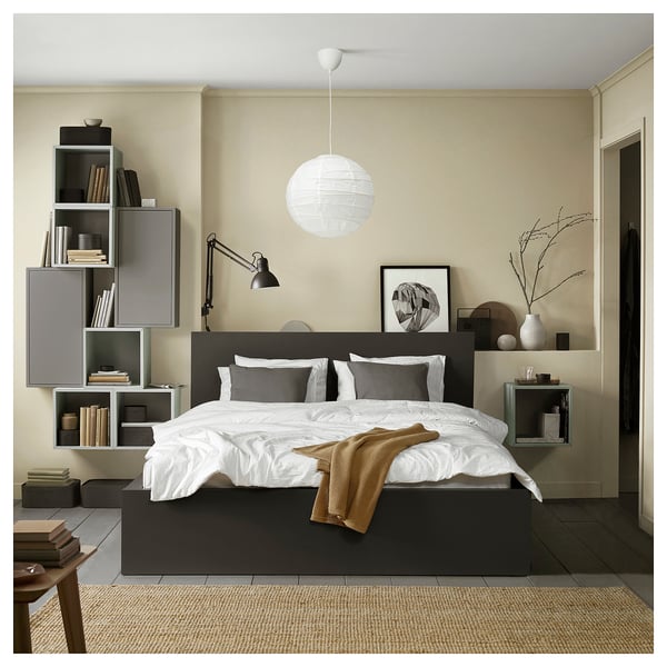 Modern minimalist bedroom with black MALM bed, white bedding, grey cushions, wall shelves, hanging lamp, and art.