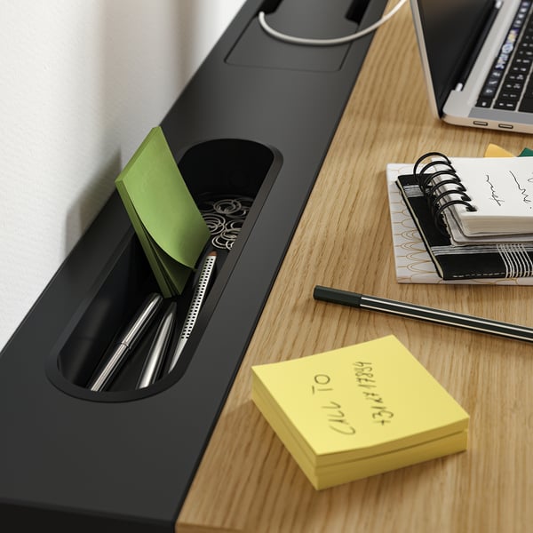 Desk organiser with pen slots, note pads, and a laptop, showing workspace efficiency.