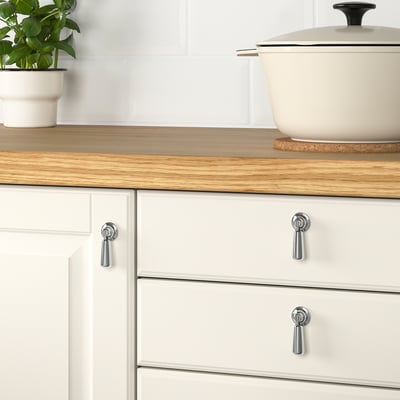 Wooden counter, white cabinets, plant on trivet.