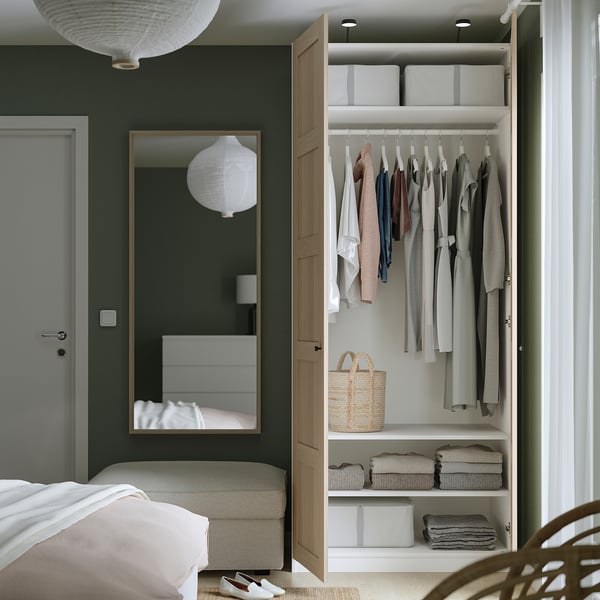Bedroom with open wardrobe, clothes, mirror, door.